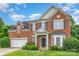 Charming brick home with a two-car garage, a covered front porch, complemented by beautiful landscaping and blue skies at 14911 Taggert Trail Dr, Charlotte, NC 28273