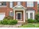 Inviting brick home entrance featuring a classic black front door, a covered porch and manicured landscaping at 14911 Taggert Trail Dr, Charlotte, NC 28273