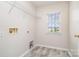 Functional laundry room area showcasing hookups, a wire shelf, durable flooring, and natural light from a window at 14911 Taggert Trail Dr, Charlotte, NC 28273