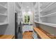 Spacious pantry with white shelving, stainless fridge, hardwood floors, and exterior view through window at 1579 Queens W Rd, Charlotte, NC 28207