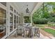 Covered patio with white brick columns, ceiling fan, comfortable seating, and view of landscaped backyard at 1579 Queens W Rd, Charlotte, NC 28207