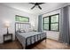 Cozy bedroom with hardwood floors, modern ceiling fan, and natural light from two windows overlooking the yard at 176 Windwood Ln, Troutman, NC 28166