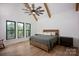Bedroom featuring hardwood floors, vaulted ceiling, wooden bed frame, and natural light from three windows at 176 Windwood Ln, Troutman, NC 28166
