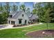 Modern farmhouse with white siding, a gray roof, black trimmed windows, and professionally landscaped yard at 176 Windwood Ln, Troutman, NC 28166