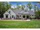 Charming white home with dark trim, stone-accented porch, professionally landscaped with green grass and mature trees at 176 Windwood Ln, Troutman, NC 28166