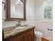 Elegant powder room with granite top, bronze fixtures, framed mirror, wainscoting, and wood floors at 20635 Queensdale Dr, Cornelius, NC 28031