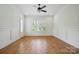 Spacious room with hardwood floors, paneled walls, large windows, and a modern ceiling fan at 20635 Queensdale Dr, Cornelius, NC 28031