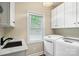 Bright laundry room with modern washer, dryer, white cabinets, and elegant marble countertop sink at 23 Tanglewood Rd, Clover, SC 29710