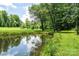 A scenic backyard pond reflecting trees and sky, surrounded by green grass and plants at 3659 Vashti Rd, Taylorsville, NC 28681