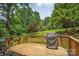Inviting wooden deck with a grill overlooking a serene, tree-filled backyard, ideal for outdoor entertaining and relaxation at 4605 Sarandon Ct, Charlotte, NC 28215