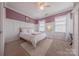 Bedroom with a mauve accent wall with white trim, neutral carpet, and filled with natural light at 5256 Meadowcroft Way, Fort Mill, SC 29708