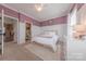 Bright bedroom with mauve accent wall, white trim, carpet, and a ceiling fan with light at 5256 Meadowcroft Way, Fort Mill, SC 29708