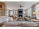 Open-concept living room with hardwood floors, a fireplace, large windows, and a ceiling fan at 5256 Meadowcroft Way, Fort Mill, SC 29708