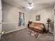 The cozy bedroom features a neutral color palette, a ceiling fan, a sofa, and a bright window at 5434 Starflower Dr, Charlotte, NC 28215