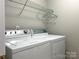Modern laundry room with white washer and dryer and overhead shelving for storage at 5434 Starflower Dr, Charlotte, NC 28215
