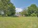 Large backyard with a lush lawn, mature trees, and the house in the background at 5632 Zion Church Rd, Concord, NC 28025