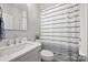 Bright bathroom with a white vanity, modern fixtures, and a striped shower curtain at 622 Mattie Rose Ln, Charlotte, NC 28204
