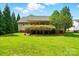 Back of house with lawn, covered back porch, and green bushes at 6530 Fly A Way Dr, Denver, NC 28037