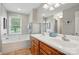 Bright bathroom featuring double sinks, a soaking tub, and a large mirror at 6530 Fly A Way Dr, Denver, NC 28037