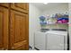 Laundry room featuring front-load machines, storage shelves, and wood cabinets at 6530 Fly A Way Dr, Denver, NC 28037