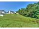 Lush green backyard with a gentle slope and mature trees, offering ample space and privacy at 6873 Lakecrest Ct, Denver, NC 28037