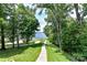 Spacious backyard with lush greenery, a winding walkway, and stunning lake views at 7010 Coventry Ct, Tega Cay, SC 29708