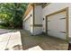 A three-car garage with white doors and a concrete driveway surrounded by trees at 7010 Coventry Ct, Tega Cay, SC 29708