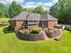 Exterior shot of the brick home featuring a screened porch, patio, and landscaped terraced garden at 7612 Maple Bluff Ln, Concord, NC 28025