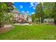 Spacious backyard featuring lush greenery, a stone patio with outdoor dining, and a greenhouse at 9514 Hayenridge Ct, Huntersville, NC 28078