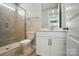 Bathroom featuring a tiled shower with glass door, neutral walls, white vanity, and a framed mirror at 9846 Quercus Ln, Huntersville, NC 28078