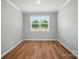 Bright bedroom with hardwood floors, a large window, neutral walls, and white trim creating a serene space at 9846 Quercus Ln, Huntersville, NC 28078