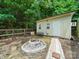 Charming backyard with fire pit, seating, green shed, and a wooded backdrop at 1015 Rhode Island Ave, Kannapolis, NC 28083
