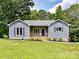 Charming blue home with a lovely wooden porch and well-manicured lawn, set against a backdrop of lush trees at 1117 Hidden Brook Ln, Clover, SC 29710