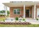Charming front porch featuring brick accents, decorative flowerbeds, and a welcoming entrance with curb appeal at 128 Hickory Ridge Dr, Locust, NC 28097