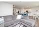 Open concept living room with modern gray couch, and a partial view of the kitchen at 128 Hickory Ridge Dr, Locust, NC 28097