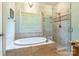 Bright bathroom features an enclosed glass shower and soaking tub under a window at 1347 Norman Dr, Rock Hill, SC 29732