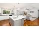 Modern kitchen boasts an island with seating, stainless sink, stylish lighting, and hardwood floors leading to the living area at 139 Hardwick Dr, Mooresville, NC 28115