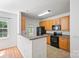 Well-lit kitchen with wood cabinets, black appliances, and a half-wall breakfast bar at 14664 Lions Paw St, Charlotte, NC 28273