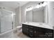 Bright bathroom featuring double sinks, dark vanity, tiled floor, and a glass-enclosed shower at 1604 Trentwood Dr, Fort Mill, SC 29715