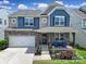 Beautiful two-story home featuring stone accents, blue siding and a charming front porch with blue chairs at 1604 Trentwood Dr, Fort Mill, SC 29715