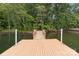 View of a wooden dock leading into a tranquil lake surrounded by lush green trees and vegetation at 165 Futrell Lndg, New London, NC 28127