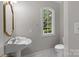Elegant powder room featuring a pedestal sink, decorative mirror, and arched window for natural lighting at 165 Futrell Lndg, New London, NC 28127