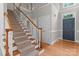 Elegant carpeted staircase with wood railing leads to the upper level; front door shown at 165 Futrell Lndg, New London, NC 28127