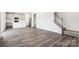 Open living room with gray hardwood floors, leading to the kitchen and staircase at 2125 Rolling Hills Ct, Stanley, NC 28164