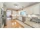 Well-lit kitchen featuring white cabinets, granite countertops, stainless steel appliances, and wood flooring at 2332 Hemby Pl, Charlotte, NC 28270