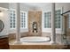 Close up of luxurious bathroom featuring a soaking tub with columns and glass block windows at 3284 Millstone Creek Rd, Lancaster, SC 29720