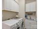 Well-lit laundry room with white cabinets, front-loading washer and dryer, and utility sink at 3284 Millstone Creek Rd, Lancaster, SC 29720