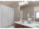 Neutral toned bathroom with a cherry wood cabinet under sink, a shower curtain, and a large mirror at 3701 Methodist Church Ln, Waxhaw, NC 28173