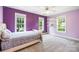 Colorful bedroom with purple and pink walls, carpet, floating shelves, and large windows offering views at 3706 Song Sparrow Dr, Matthews, NC 28104