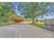 A red barn situated beside a large tree and a spacious yard with a deck that's perfect for outdoor activities at 37156 Southside Rd, Albemarle, NC 28001